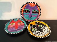 Three colourful cat motif plates with checkerboard rims