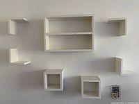 full view of all seven white floating shelves mounted on wall