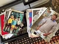 Stack of assorted knitting pattern booklets on table