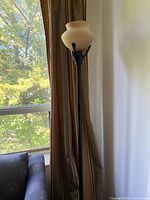 Full view of floor lamp in front of window and curtains
