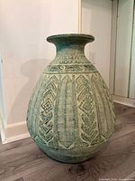 Front view of large carved clay urn showing overall design and condition