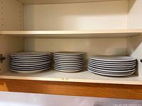 Three stacks of large and medium plates on shelf