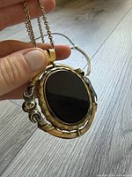 Front view of necklace showing black oval cabochon and gold-tone rotating frame