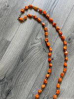 Full length of necklace laid out showing orange stone beads and crystal spacers