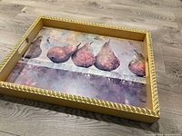 Front view of wooden tray showing pear artwork and decorative rope frame