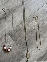 All three silver-tone necklaces laid out for full view of chain types, beads and pendant
