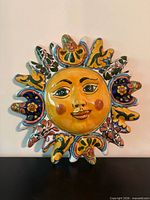 Full view of ceramic sun face sculpture showing overall design and colors