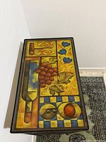 Close-up of glazed ceramic tile top with fruit and kitchen motif