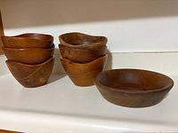 Stack of six small wooden bowls alongside one larger wooden bowl