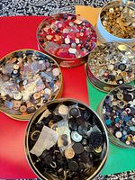 Top view of six tins showing assorted button colors and materials