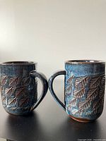 front view of both mugs showing glaze and relief pattern