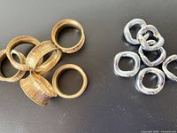 Both sets of napkin rings displayed: brass embossed rings on left, silver-tone irregular rings on right