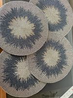 Stack of four round beaded placemats showing starburst design