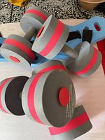 Stacked grey and red foam dumbbells with blue belt visible