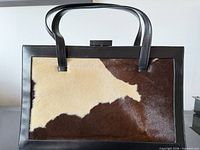 Front view showing calf hair panel, leather frame, handles, clasp