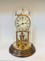 Front view of Kundo clock under dome on wood base