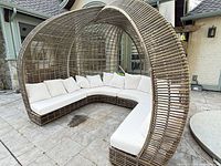 Full view of wicker canopy sectional daybed with cushions in outdoor setting