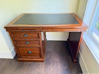 Full view of desk showing drawers, open knee space and leather inset top