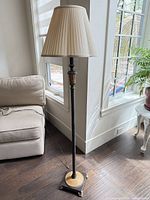 Full view of lamp with shade beside sofa