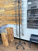 Full view of tall black wire greeting card rack on five-caster base
