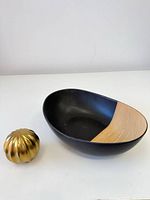Top view of black ceramic bowl with wood panel and gold accent piece