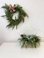 Wreath on wall above matching greenery centerpiece in wood box