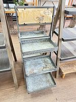 Front view of four-tier galvanized metal plant stand showing trays and frame