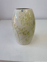 Front view of cream vase with green embossed leaves