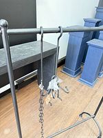 Front view of black metal garment rack with S-hooks and chain hanging