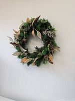 Full view of artificial green and gold wreath on wall