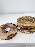 Three wooden round plant stands, two stacked, one upside down