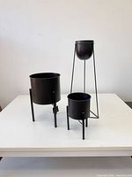 Front view of all three black metal plant stands showing relative heights