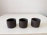 Front view of three small charcoal concrete planters