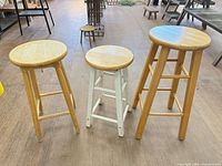 Front view of three wooden stools showing heights and finishes