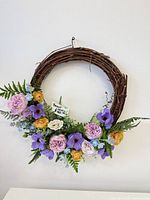 Full view of grapevine wreath with floral arrangement and tag