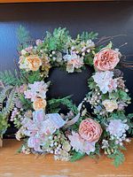 Full view of floral grapevine wreath showing flowers, greenery and ribbon