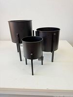 Front view of all three black matte metal plant stands