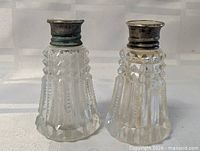 Front view of both faceted glass shakers showing sterling tops