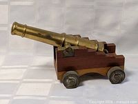 Three-quarter view of brass cannon on wood carriage
