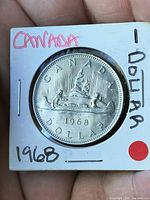 Reverse of 1968 Canada dollar in holder showing Voyageur design and date