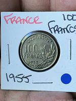 Reverse of coin showing denomination 100 FRANCS 1955 within 2x2 flip