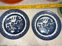 Front view of two Blue Willow dinner plates with measuring tape showing size