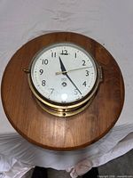 Front view of Smiths Astral brass wall clock on wood board