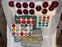 Overview of bin with multiple trays of glass ornaments in various colors