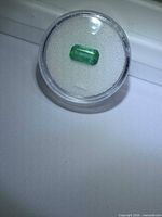 Emerald in display capsule showing overall size and color