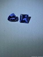 Trillion and princess cut tanzanite gemstones on neutral background