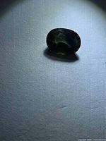 Top view of oval blue-green sapphire on neutral background
