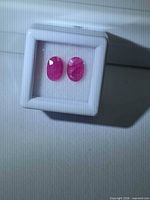 Pair of loose bright pink oval rubies in gem box
