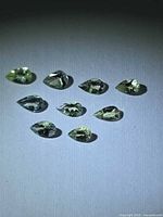 Nine pear-cut lemon-lime tanzanites arranged on flat surface