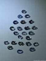 All stones arranged in triangular layout showing assortment of oval tanzanites